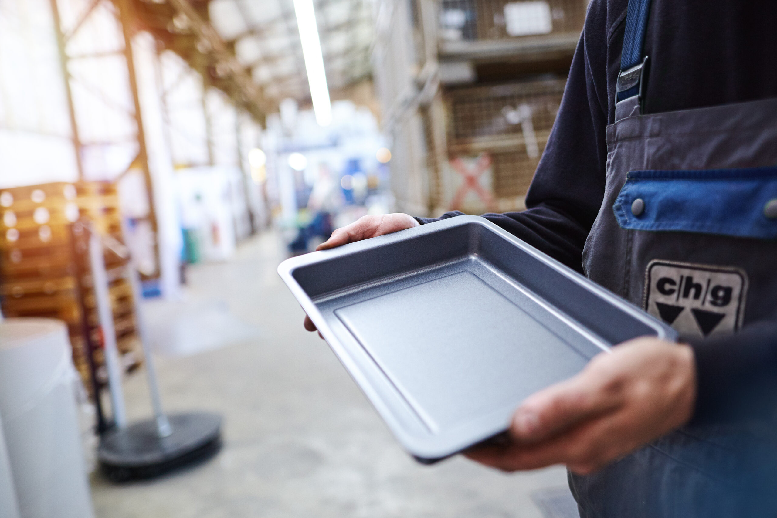 Produktbilder für SEO optimieren Mitarbeiter hält eine rechteckige Metallform in einer Produktionshalle