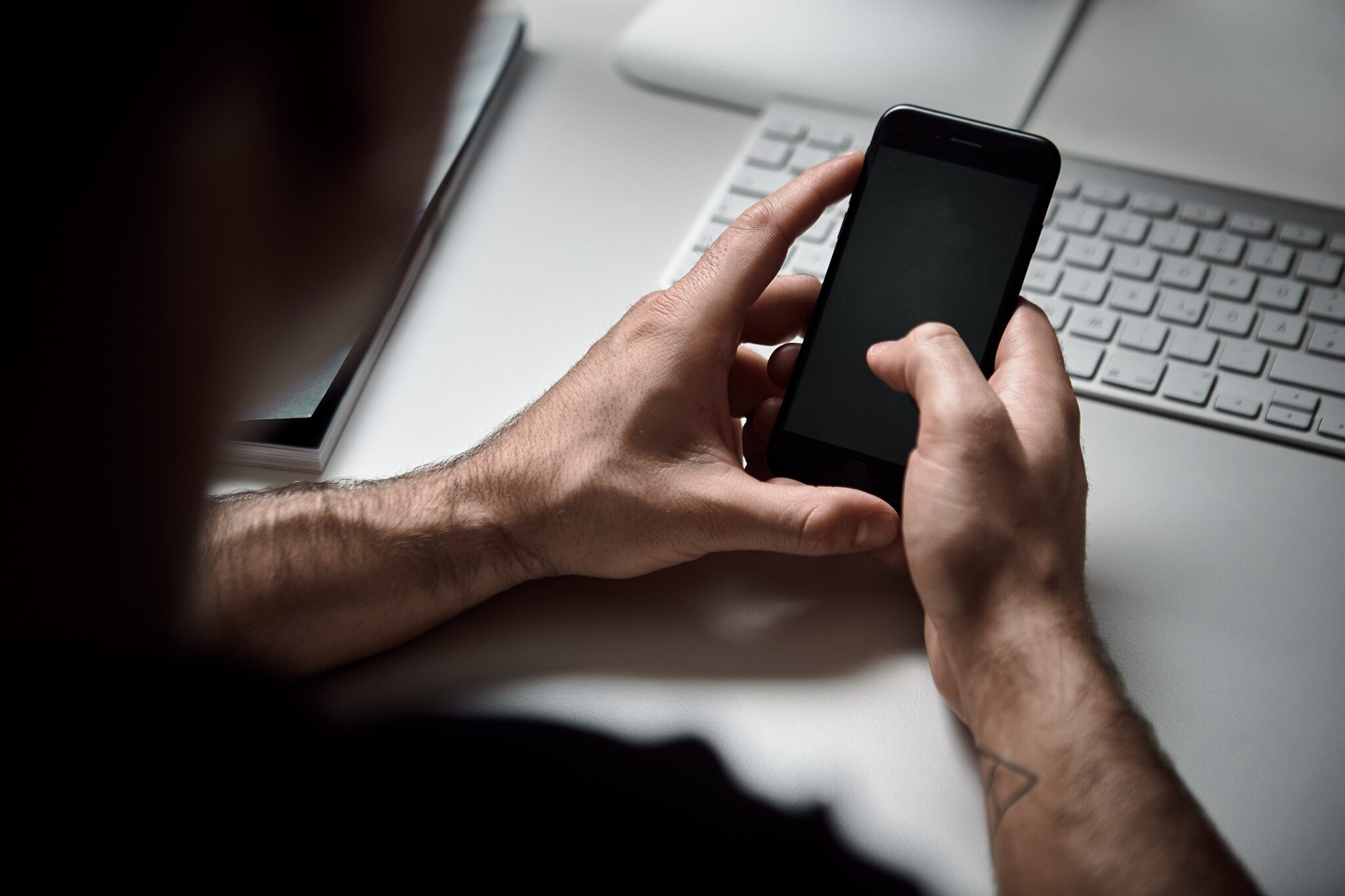 Mitarbeiter von Denkagil bedient ein Smartphone an einem Büroarbeitsplatz