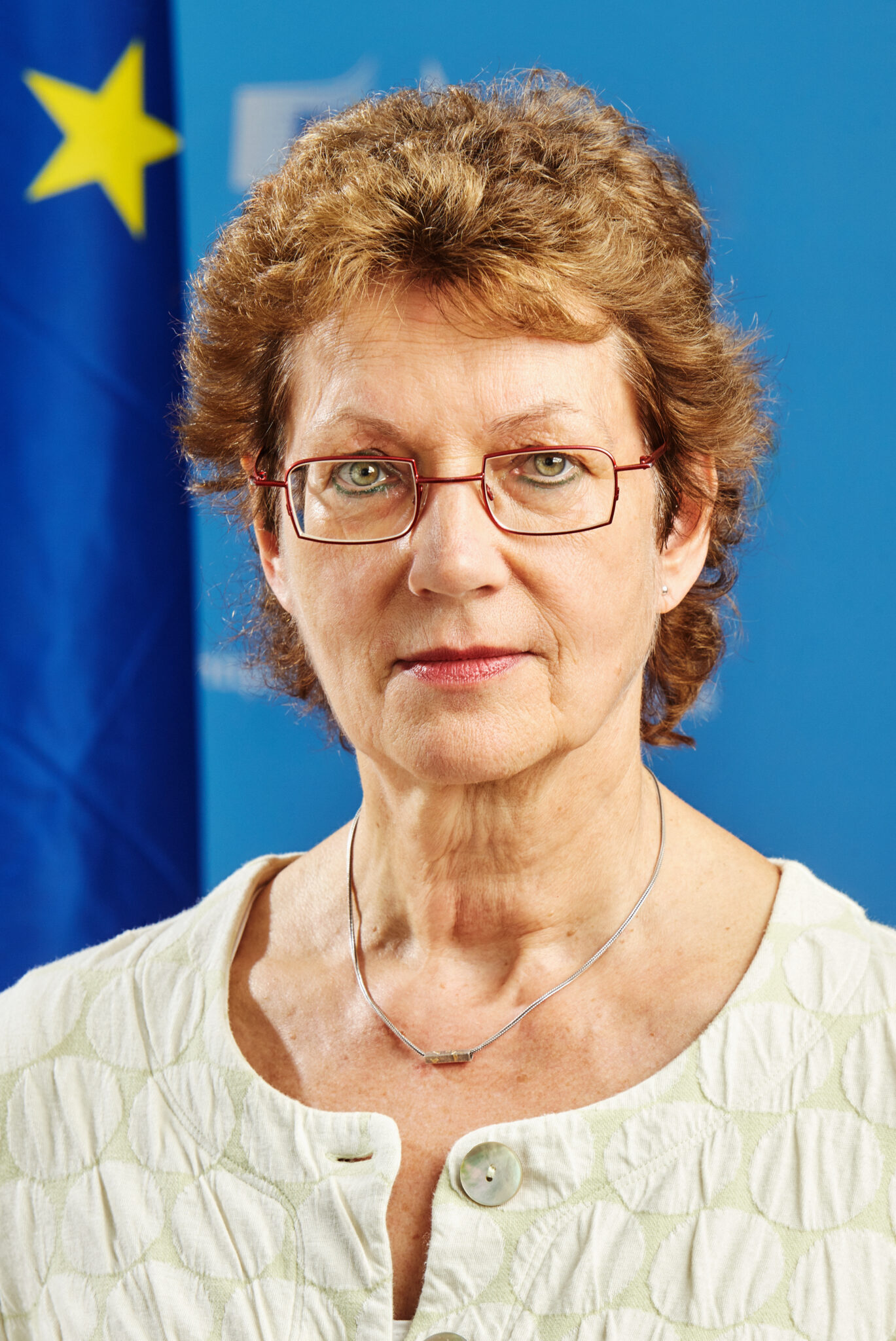 Porträt einer Frau vor EU-Flagge und Hintergrund der Europäischen Kommission