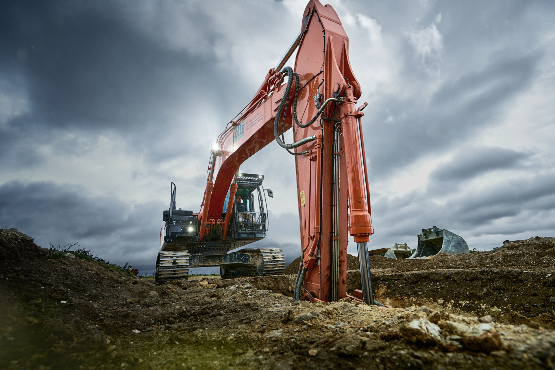 Großer Kolle-Bagger auf einer Tiefbaustelle unter dunklem Wolkenhimmel