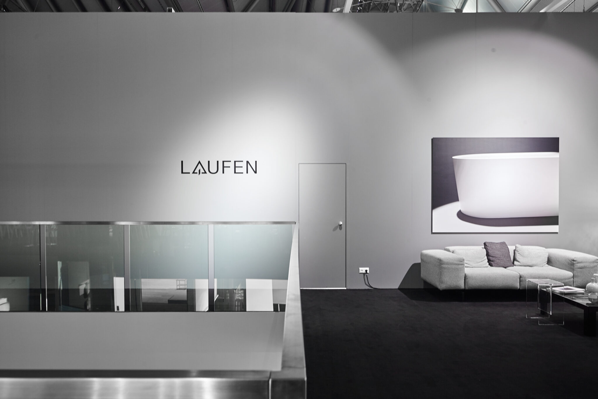 Loungebereich im LAUFEN-Showroom mit Sofa, großformatigem Produktmotiv und beleuchtetem Markenlogo