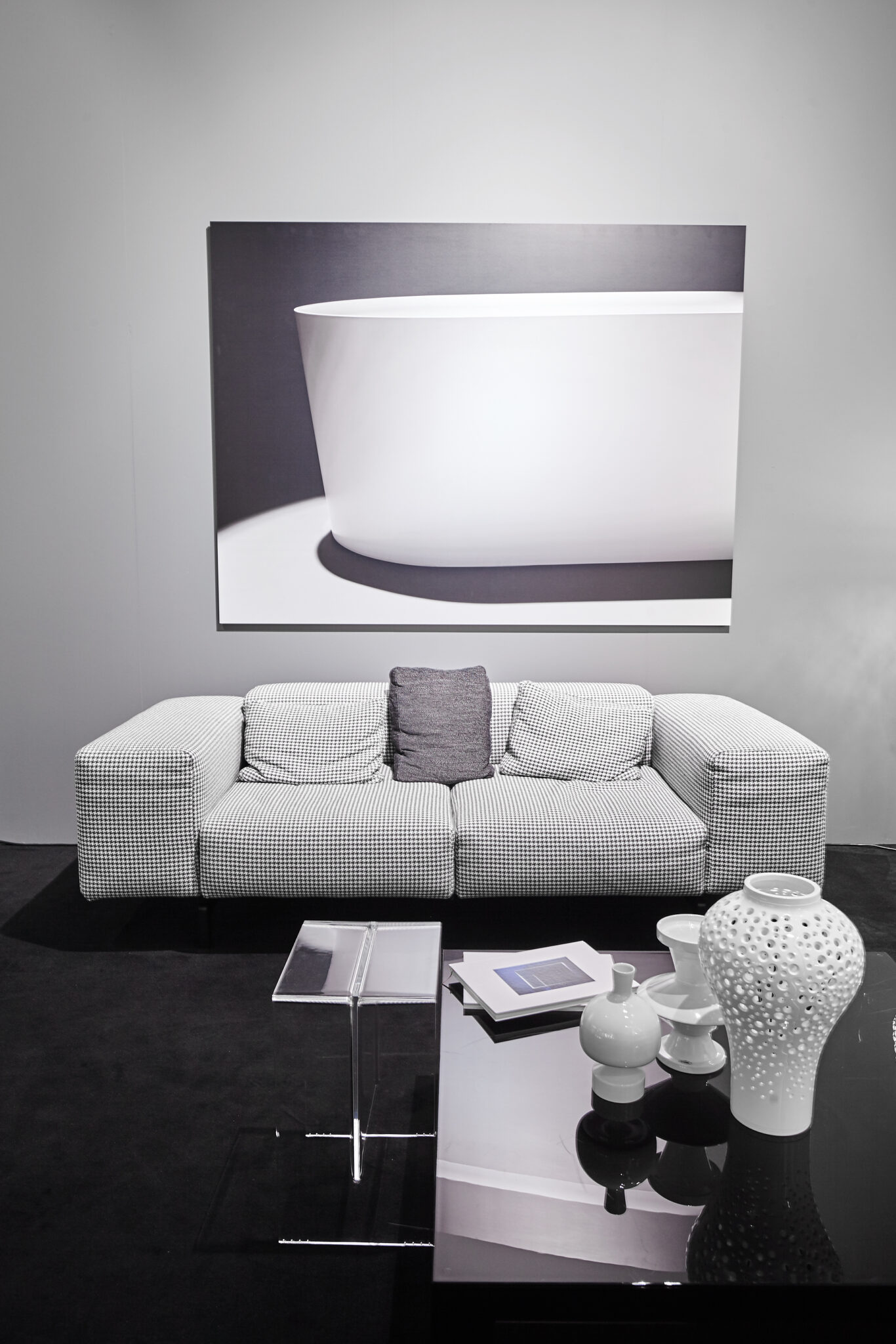 Lounge im LAUFEN-Showroom mit weißem Sofa, Glastisch und großformatigem Badewannenmotiv