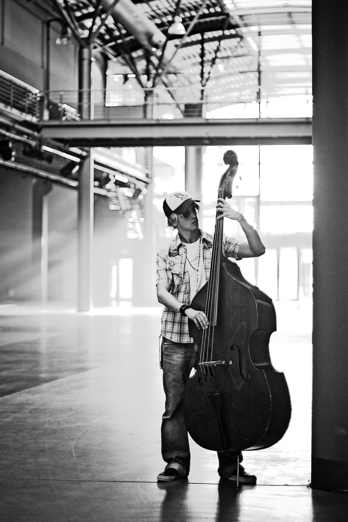 Kontrabassist steht mit seinem Instrument in einer großen Industriehalle