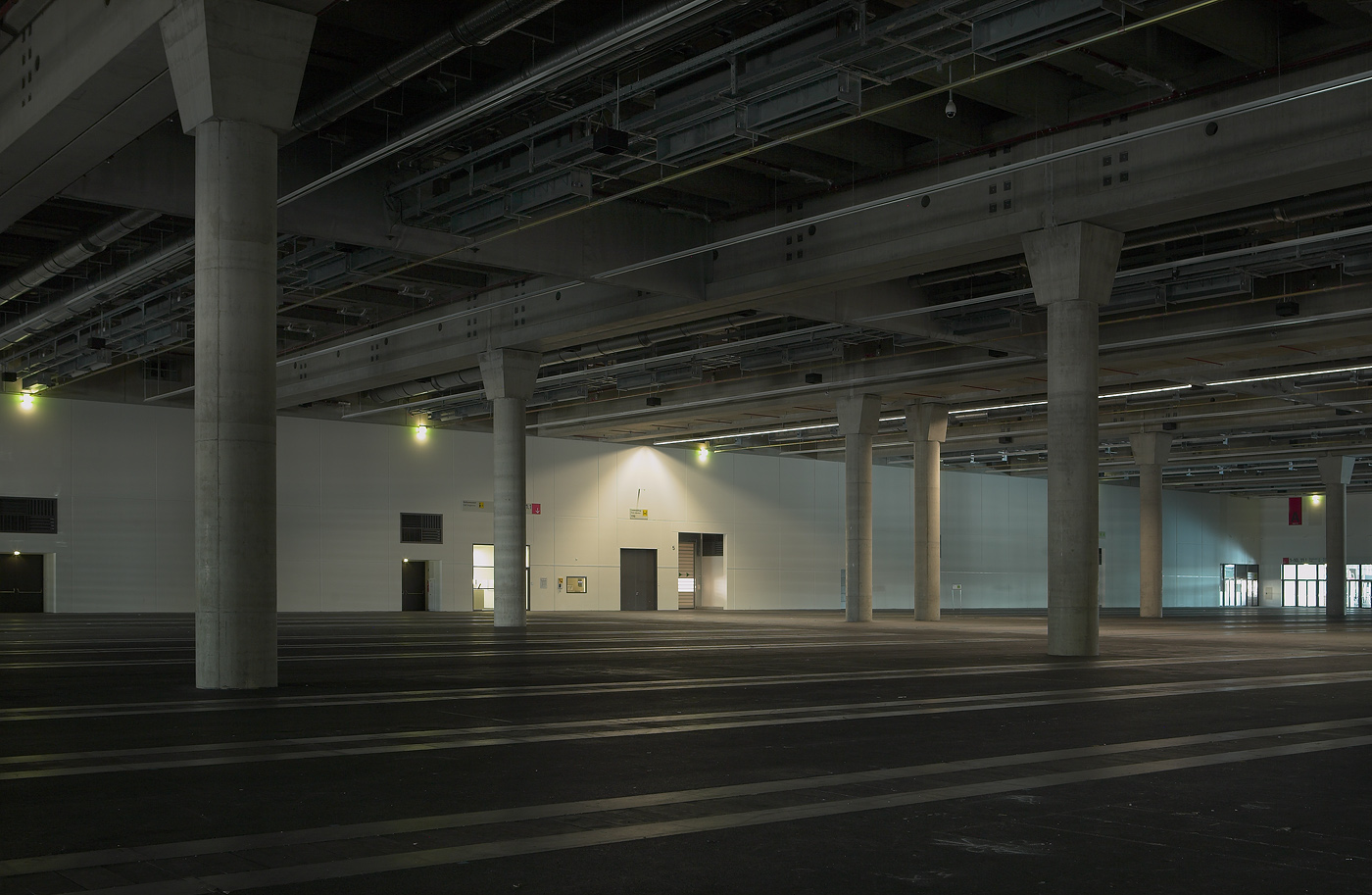 Leere weitläufige Halle mit regelmäßigen Säulenreihen und sichtbarer Deckenkonstruktion