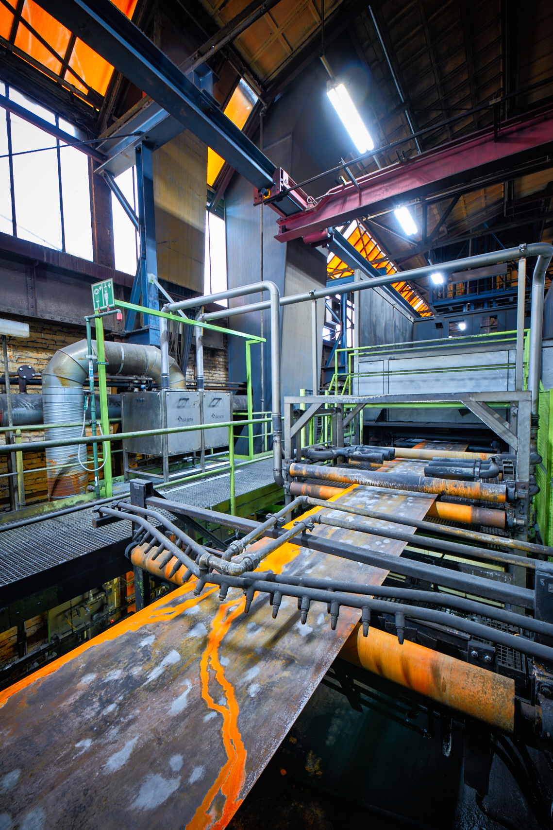 Metallband auf Rollen in einer industriellen Fertigungsanlage mit Rohrleitungen