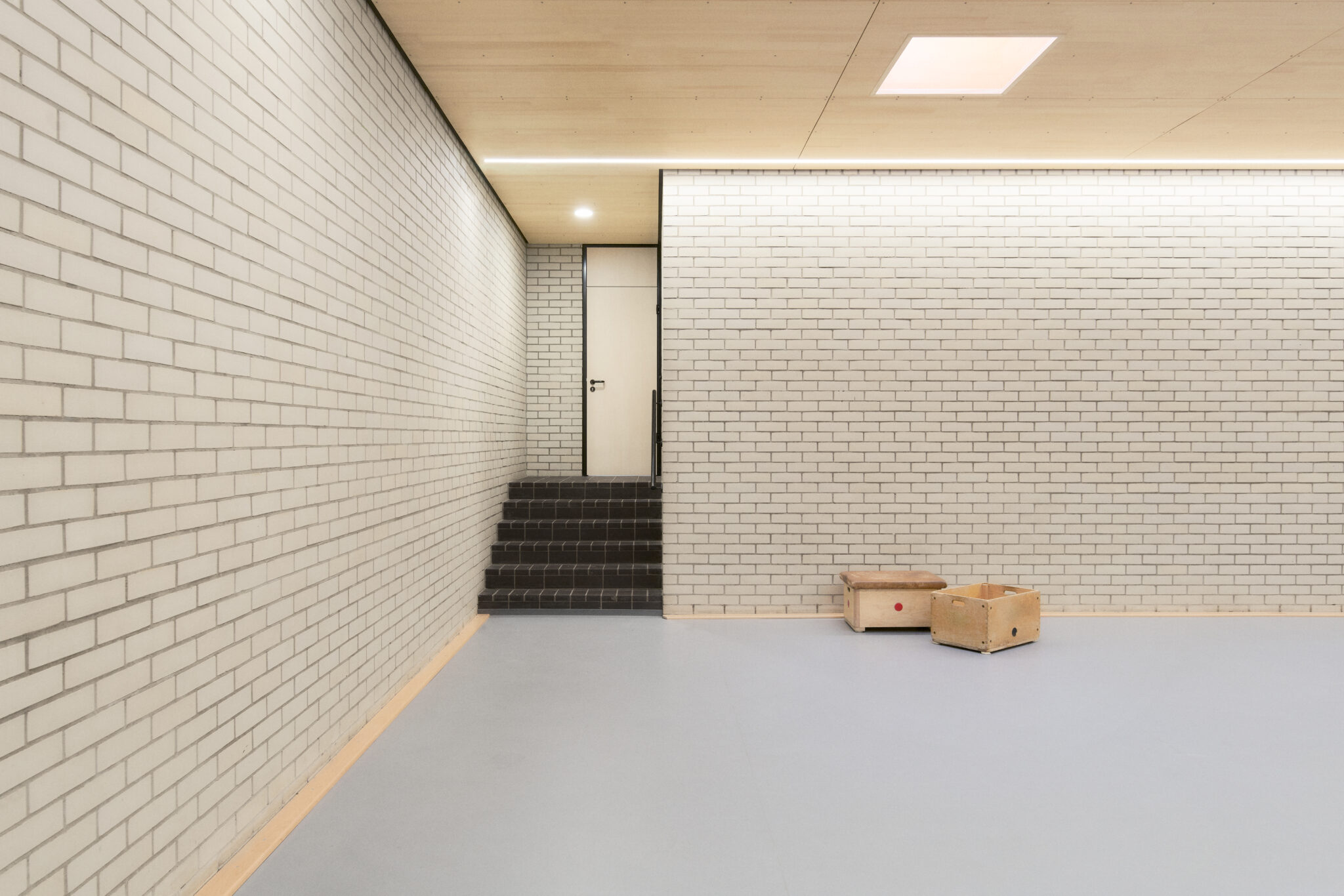Innenraum der Sporthalle II mit heller Klinkerwand, Holzdecke und kleinem Treppenaufgang