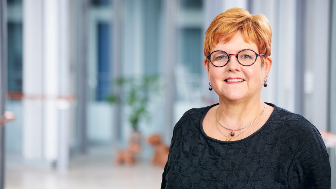 Portrait einer Johanniter-Mitarbeiterin mit Brille in einem hellen Innenraum