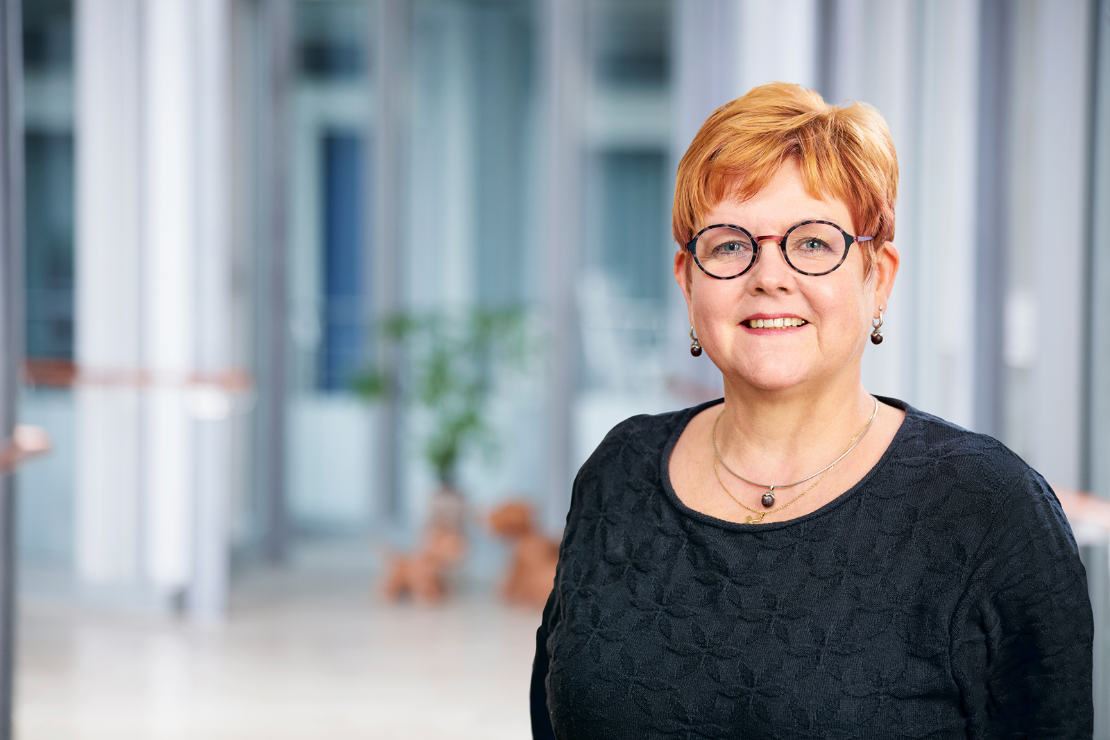 Portrait einer Johanniter-Mitarbeiterin mit Brille in einem hellen Innenraum