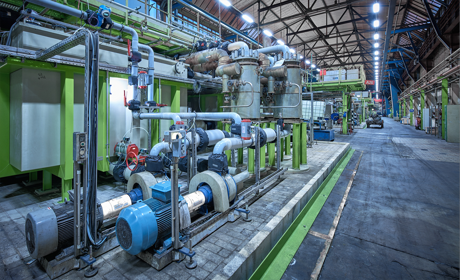 Pumpen, Rohrleitungen und Behälter einer Industrieanlage in einer Produktionshalle