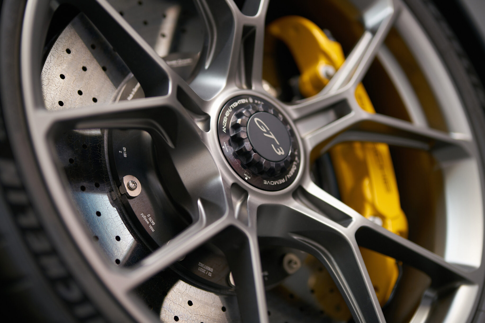 Nahaufnahme einer Porsche-GT3-Felge mit gelochter Bremsscheibe und gelbem Bremssattel