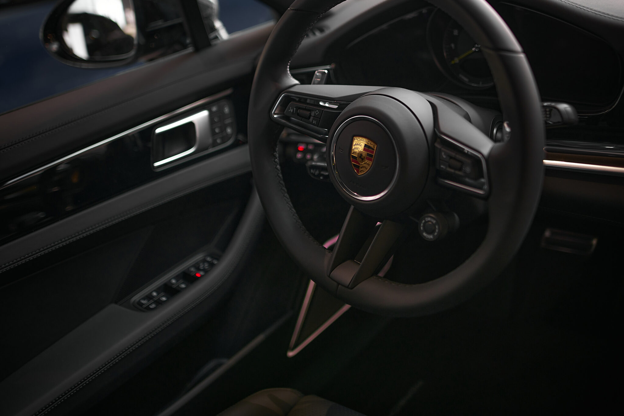 Porsche-Interieur mit schwarzem Lenkrad, Markenemblem und Cockpit