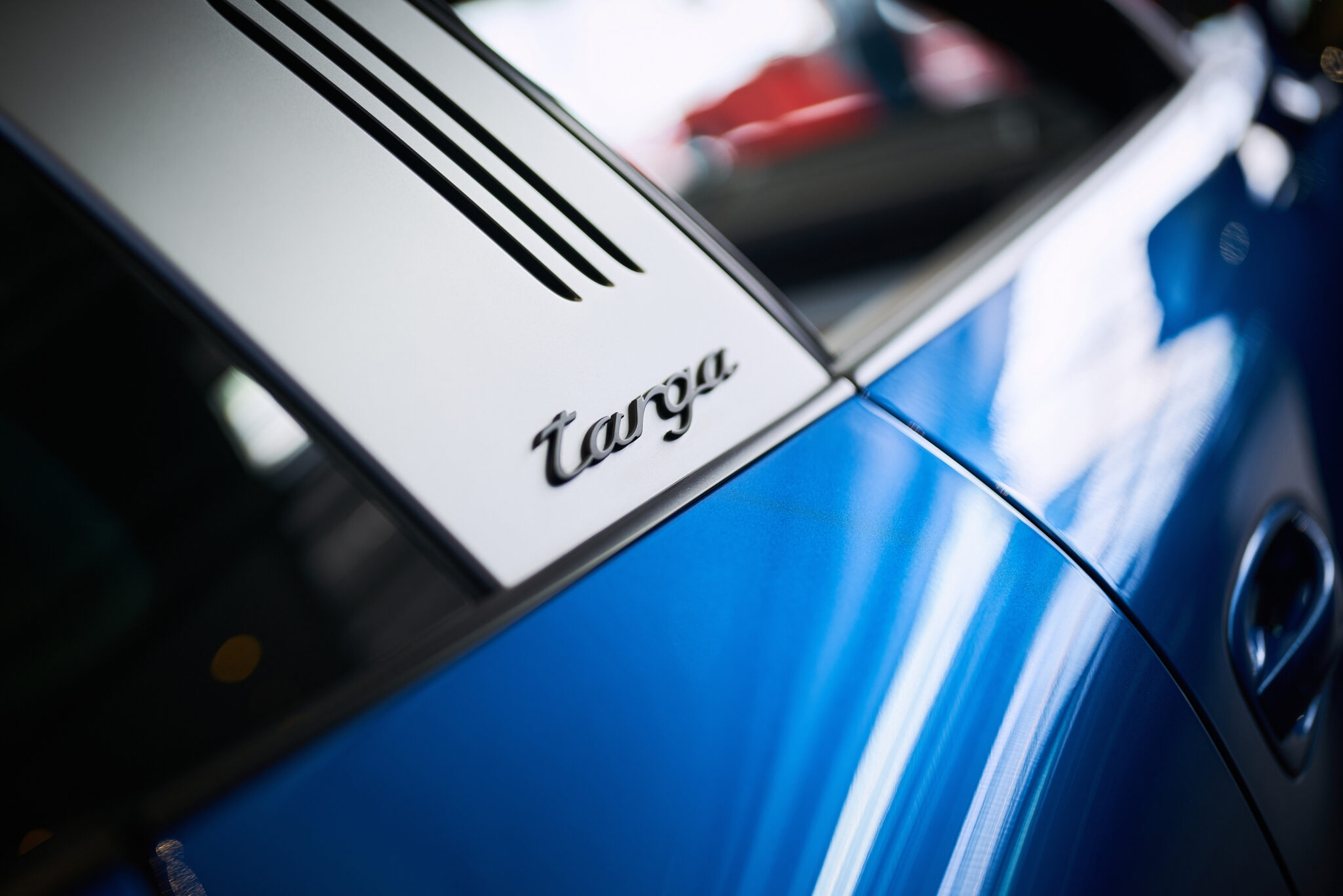 Porsche-Targa-Schriftzug an einer blau lackierten Karosserie in Nahaufnahme