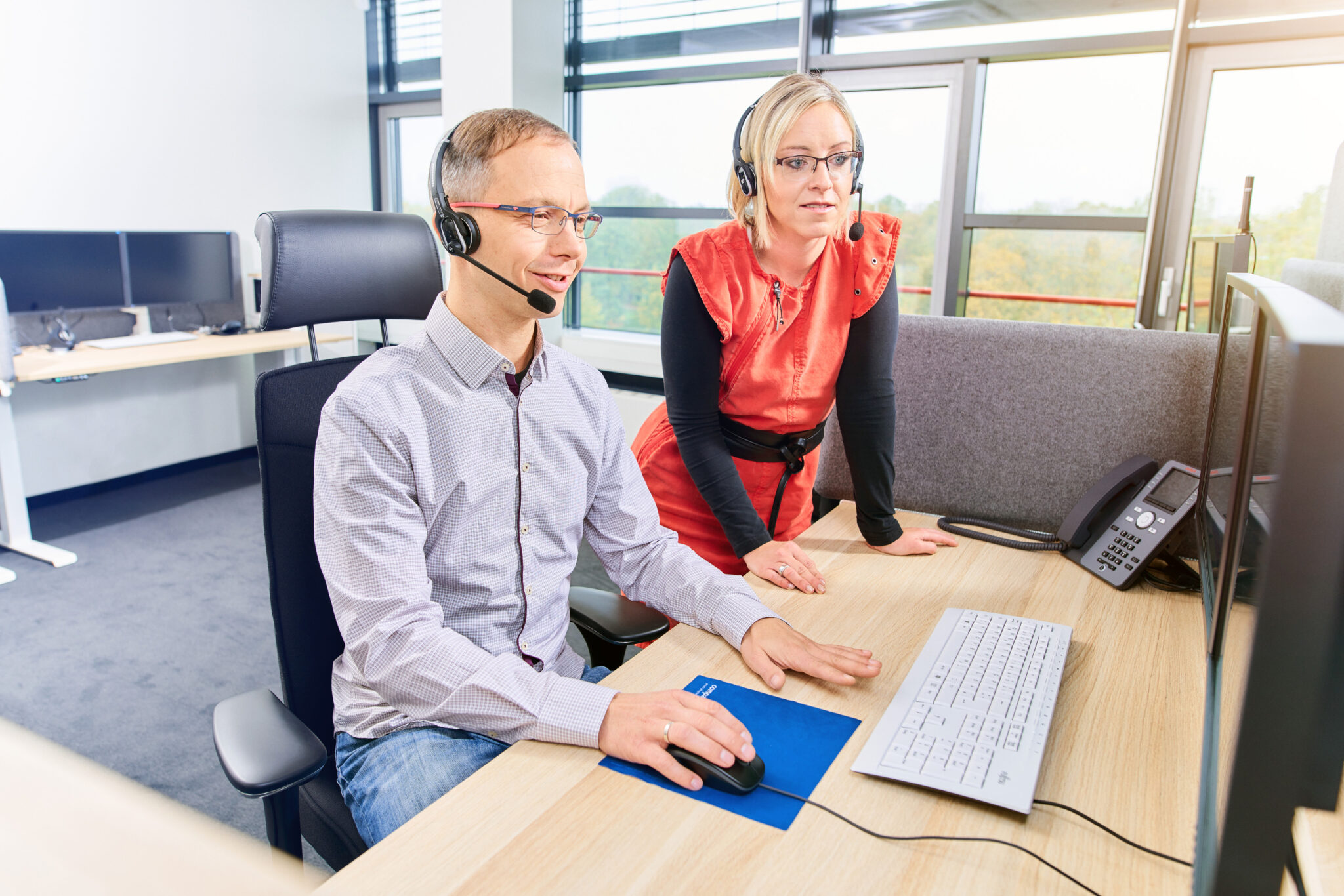 Zwei Mitarbeitende von Compass Pflegeberatung gemeinsam an einem Kundenservice-Arbeitsplatz